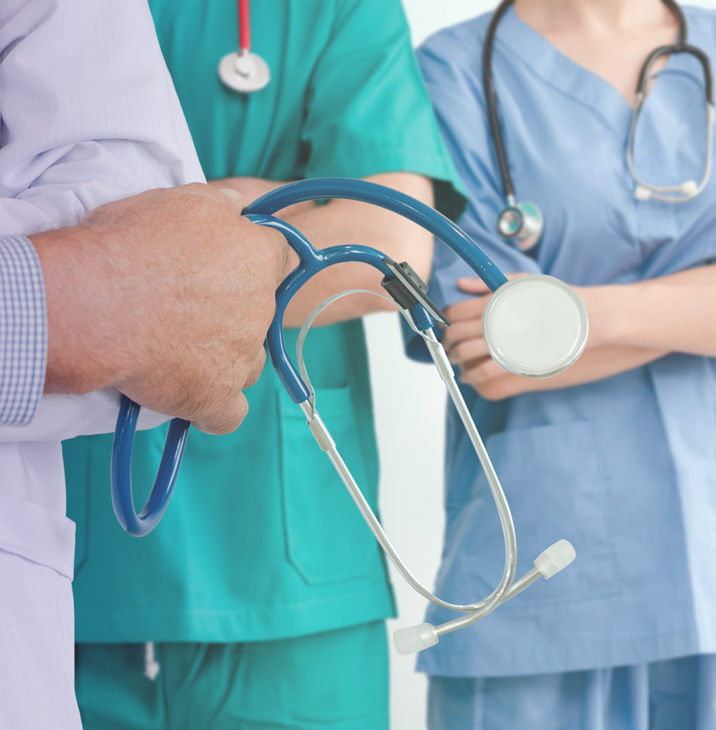Lähikuva kolmesta terveydenhuollon ammattilaisesta työasuissaan ja stetoskoopit kaulalla tai kädessä.
