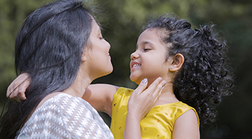 Äiti pitää lasta sylissä katsoen häntä silmiin.