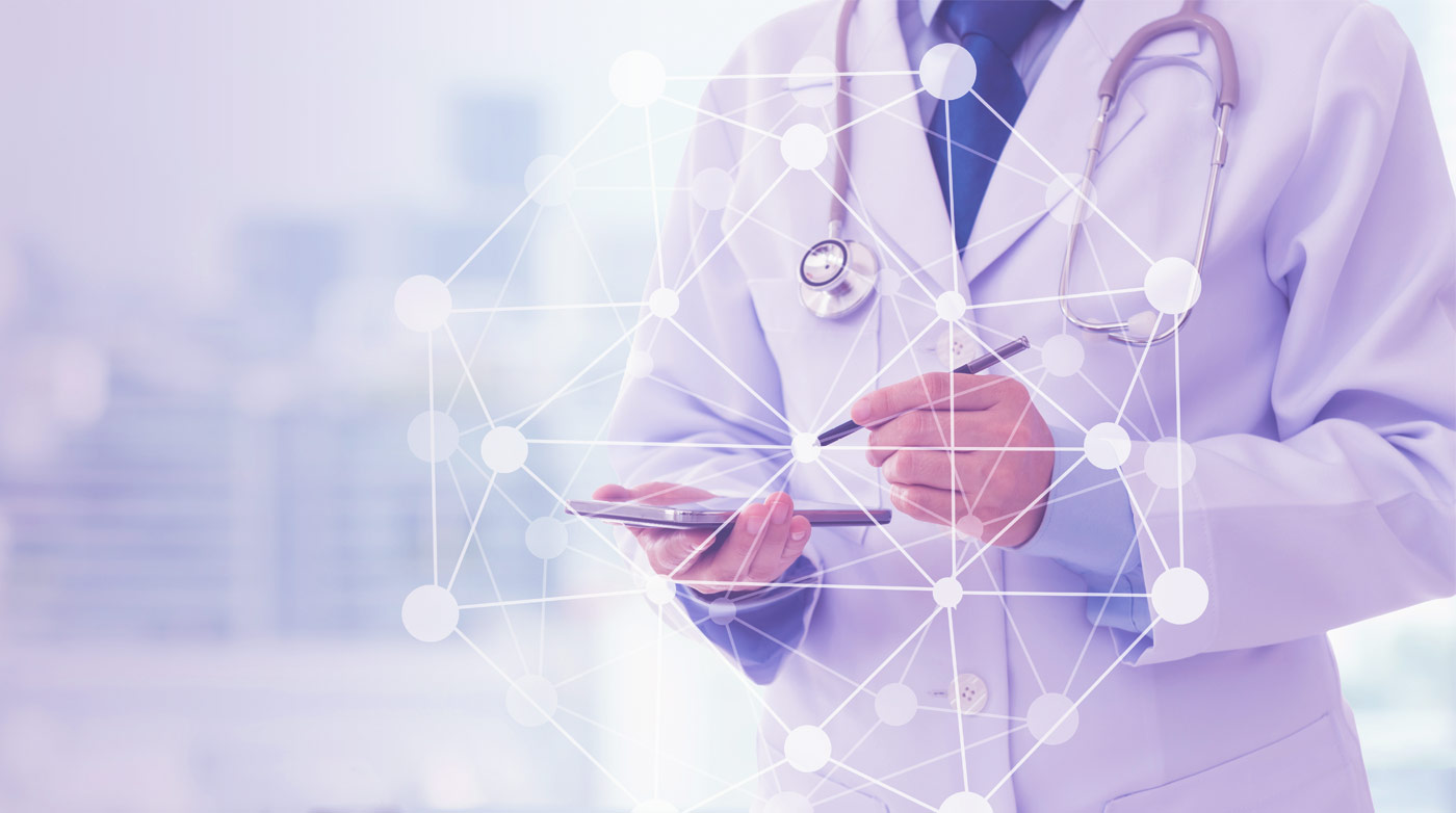 Valkotakkinen lääkäri stetoskooppi kaulalla, älylaite kädessä.